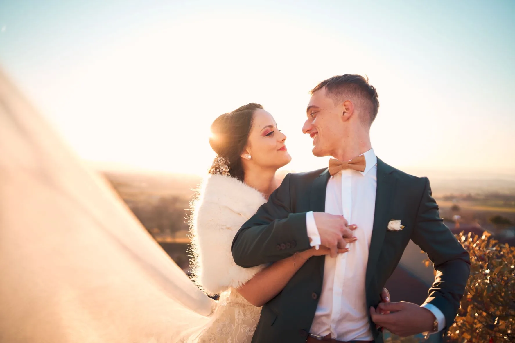 Couple de mariés au coucher du soleil dans un paysage naturel.